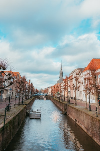 During the day and cloudy sky river between the houses
